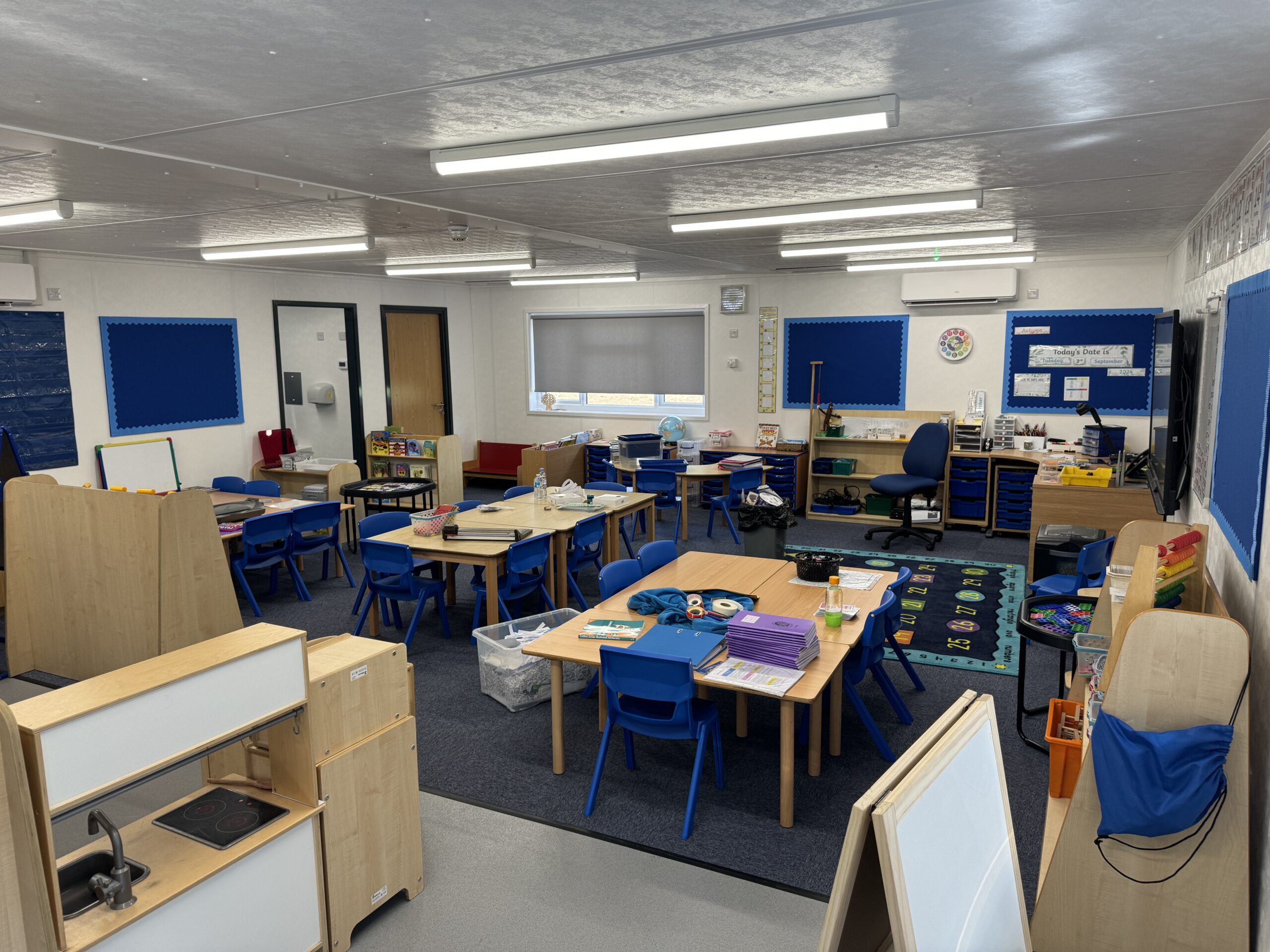 image shows a modular classroom building with desks and information boards