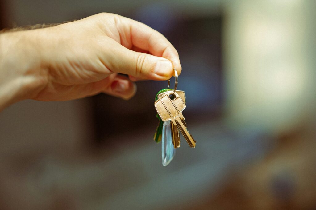 A hand coming from the left holding a bunch of keys on a dark blurry background.